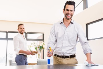 Fototapeta na wymiar Smiling gay couple cleaning living room 