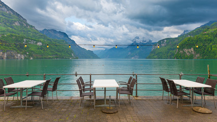 Fototapeta na wymiar Town of Brunnen in central Switzerland. Cafe on the lake. Chairs and desks.