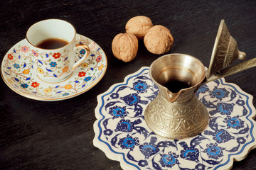 Coffee cup, walnuts and Turkish style cezve with tasty drink on blue tray