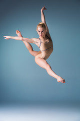 Obraz premium Young beautiful modern style dancer jumping on a studio background