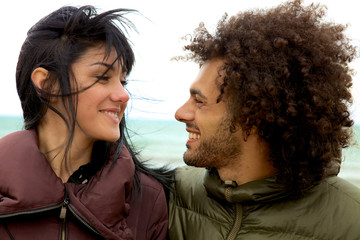 Couple in winter with wind looking at each smiling happy