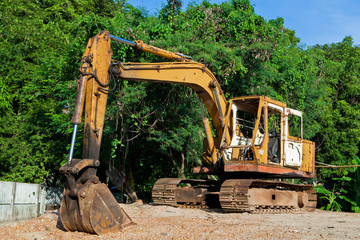 Yellow excavator at the forest and blue sky