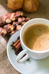 Coffee mug with cinnamon stick chocolate and biscuits. Soft focus.