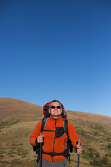 Man hiking in the mountains with a backpack and tent.