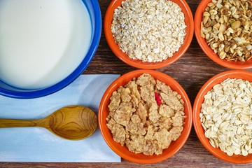 Four small bowls with different cereals and bowl with milk, healthy foodFour small bowls with different cereals and bowl with milk, healthy food