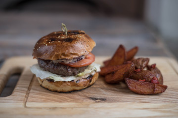 Burger with meat cutlet is on the board and chips