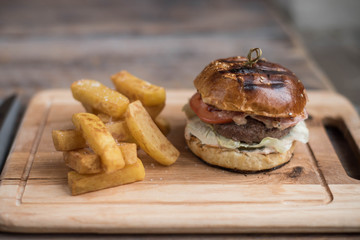 Burger with meat cutlet is on the board and chips