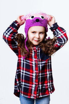 A little girl is in the cap of mouse. Studio photo