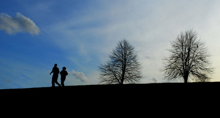 Fototapeta premium Winter landscape with silhouettes of runners on a horizon at sunset