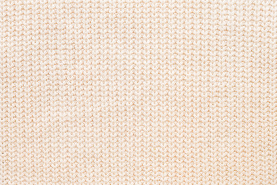 Abstract knitted background. Wool beige sweater texture. Close up