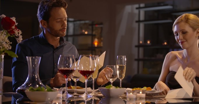 Beautiful elegant couple choose what to eat in a restaurant in the evening in slow motion (in realtime at 60 fps)