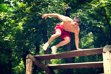 Athlete jumping over the fitness trail obstacle 