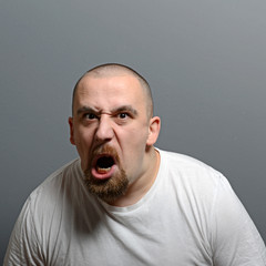 Portrait of a angry man screaming against gray background