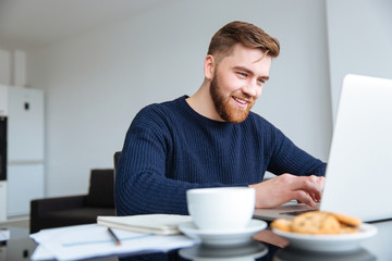 Smiling man using laptop computer at home