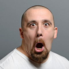 Portrait of a man making funny face against gray background - 101240144