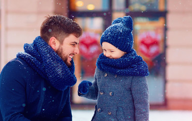 portrait of happy father and son under winter snow