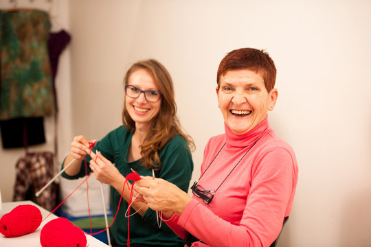 Women knitting with red wool. Eldery woman transfering her knowl