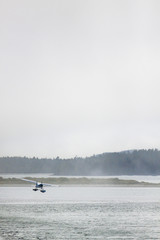 Obraz na płótnie Canvas Float Plane takes off in Foggy Coastal Weather