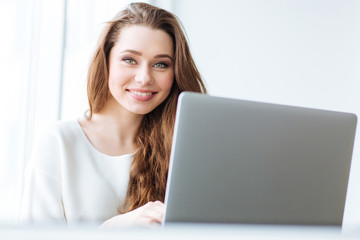 Cheerful woman sitting at the table with laptop