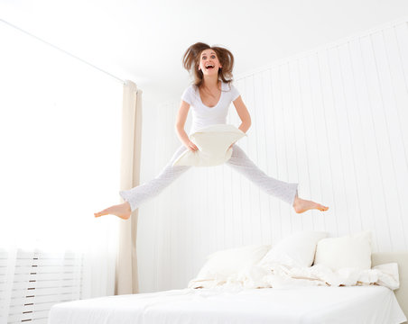 happy girl jumping and having fun in bed