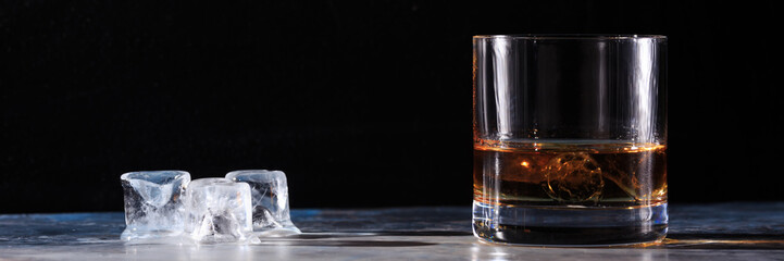 Glass of whiskey with ice on the table