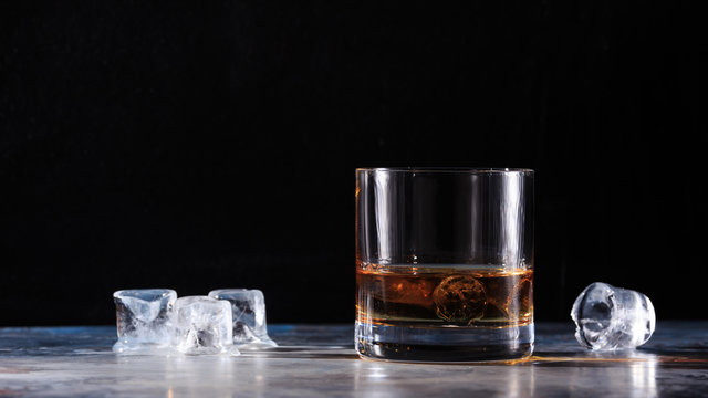 Glass of whiskey with ice on the table