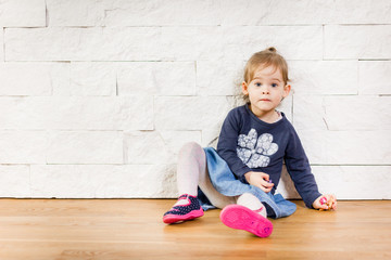 Beautiful child sitting against the wall