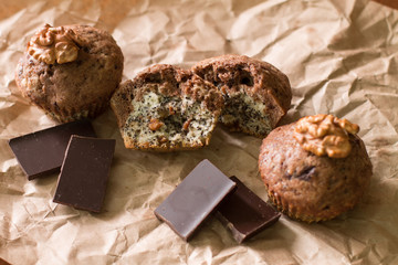 Bicolor muffin with chocolate, poppies and walnuts on paper.