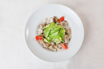 salad with meat in a creamy sauce, ase, lettuce, romaine, iceberg cherry tomatoes on top of the plate isolated 