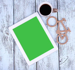 Tablet pc and mug of coffee on wooden background