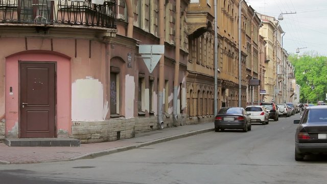 View of a street corner with road signs, people and cars in summer evening