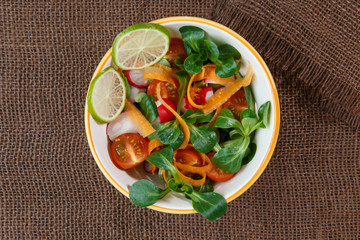 Bowl of fresh vegetable salad on jute table cloth
