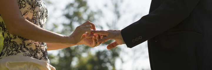 Wedding ceremony - closeup view of a bride placing a ring on her