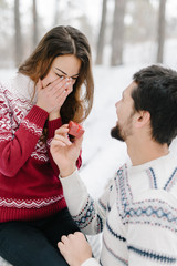 Handsome caucasian man doing a marriage proposal on bright winter day in the park for the valentines day
