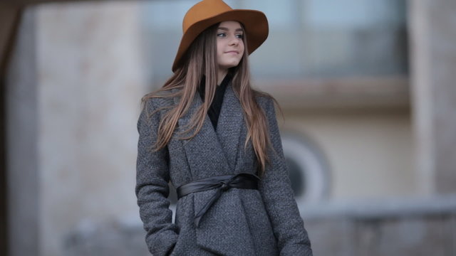 beautiful girl in a hat with a brim and a coat with a smartphone