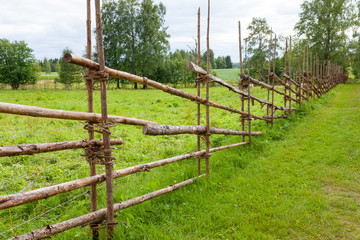 Old traditional wooden fence and meadow