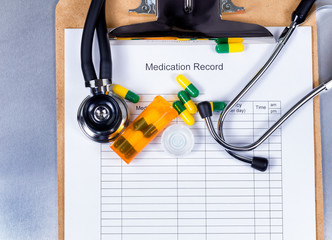 Clipboard with patient medication record plus pills 
