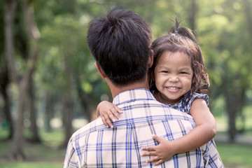 happy little girl resting on her father's shoulder