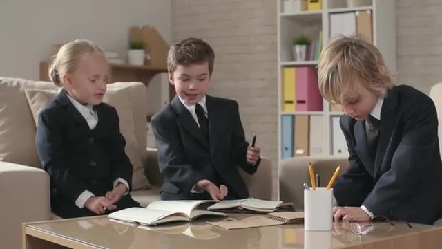 Adorable business children sitting at the office table and taking some notes