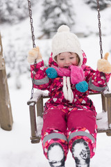 little girl at snowy winter day swing in park