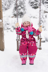 little girl at snowy winter day swing in park
