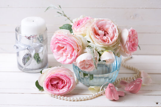Pink roses flowers  in blue vase on white painted wooden backgro