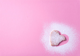 Heart shaped cookie with sugar icing on a pink paper background