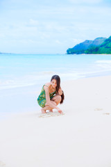 Fototapeta na wymiar Beautiful teen girl drawing heart in sand on tropical beach