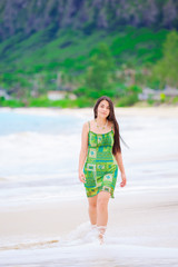 Fototapeta na wymiar Beautiful teen girl in green dress walking along Hawaiian beach