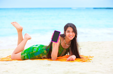 Beautiful biracial teen girl lying on tropical beach with phone - Powered by Adobe