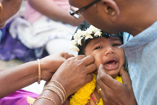 Baby girl crying in Hindus ear piercing ceremony