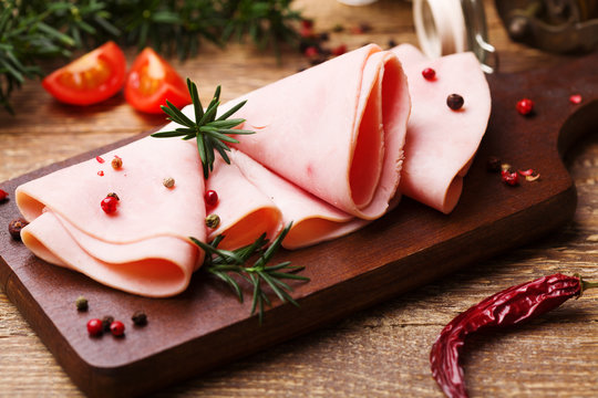 Delicious cooked ham on a wooden board with spices.