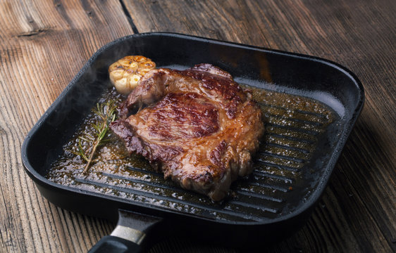 Grilled ribeye steak on a grill pan with rosemary and garlic