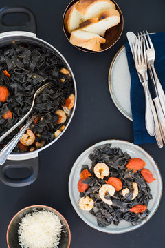 Homemade black squid ink tagliatelle with tomatoes and shrimps sauce